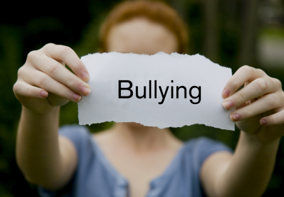 A girl holding out the word bullying on a slip of paper